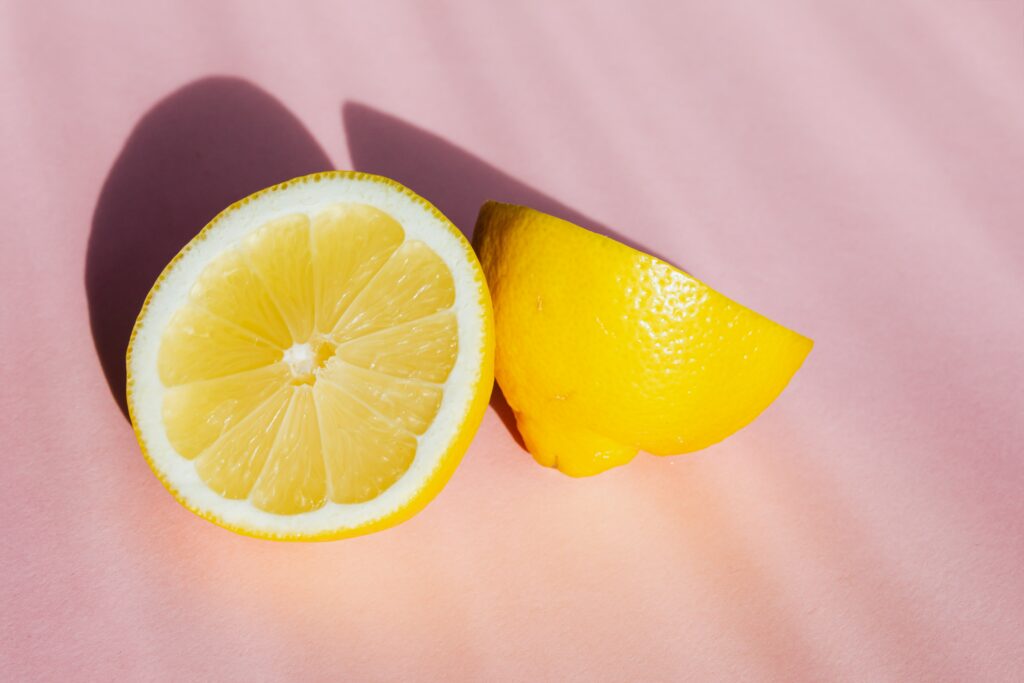 A lemon cut in half on a pink background.
