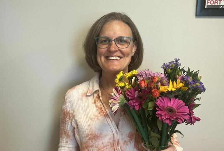 Jackie Gibbons poses with flowers for National Volunteer Month.