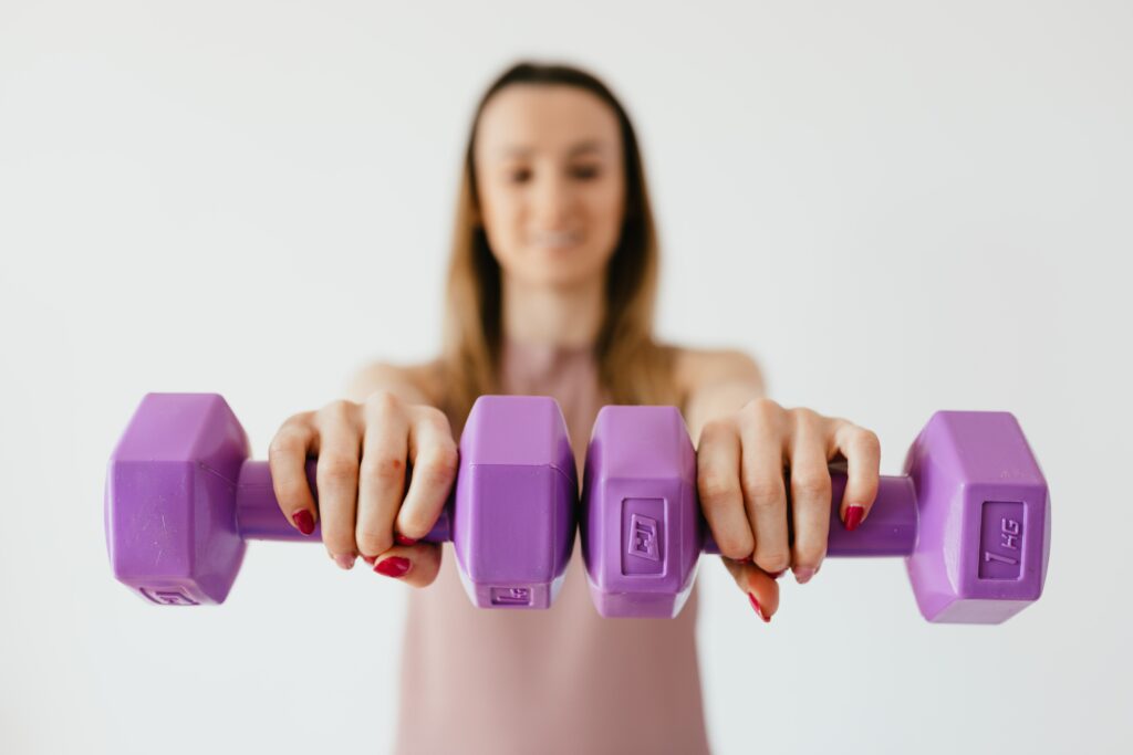 A woman participating in ForeverFit is holding light, purple weights
