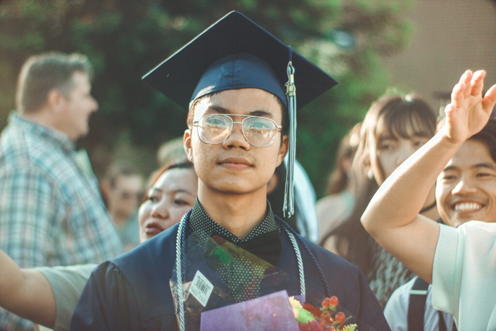 A young asian man wearing academic dress graduating. He was awarded a scholarship from the Ruth Cheatham Foundation.