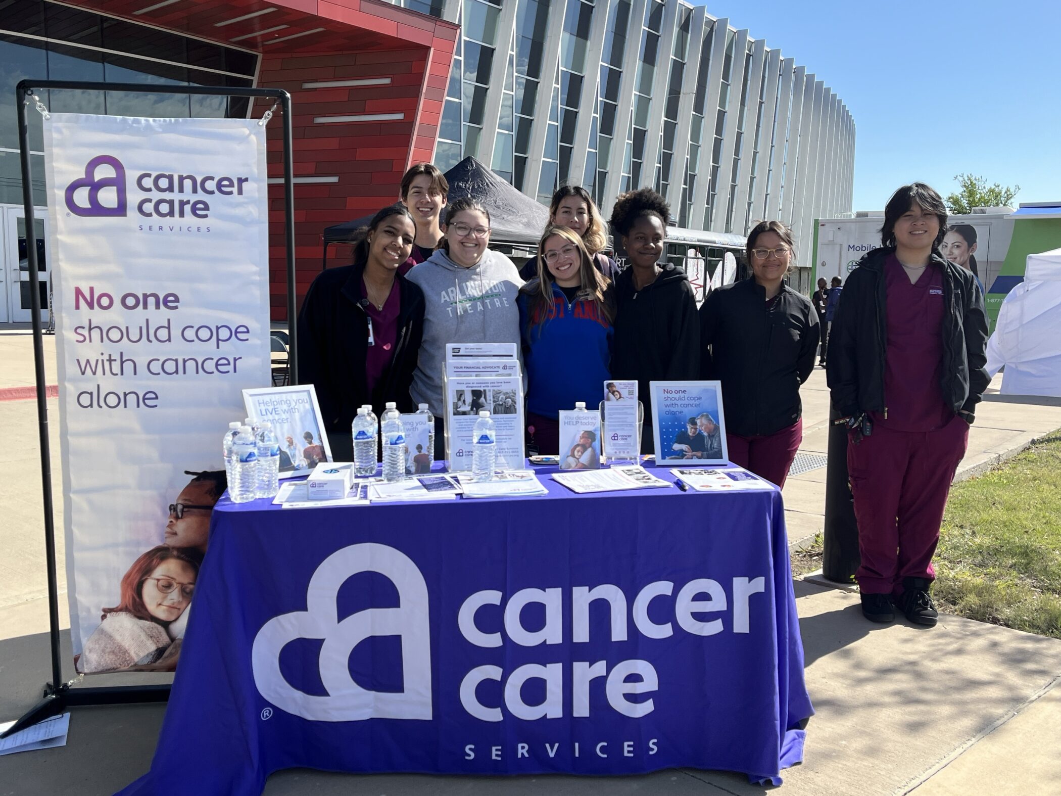 Cancer Care staff and interns pose behind a booth at at 2024 health expo and community screening event.