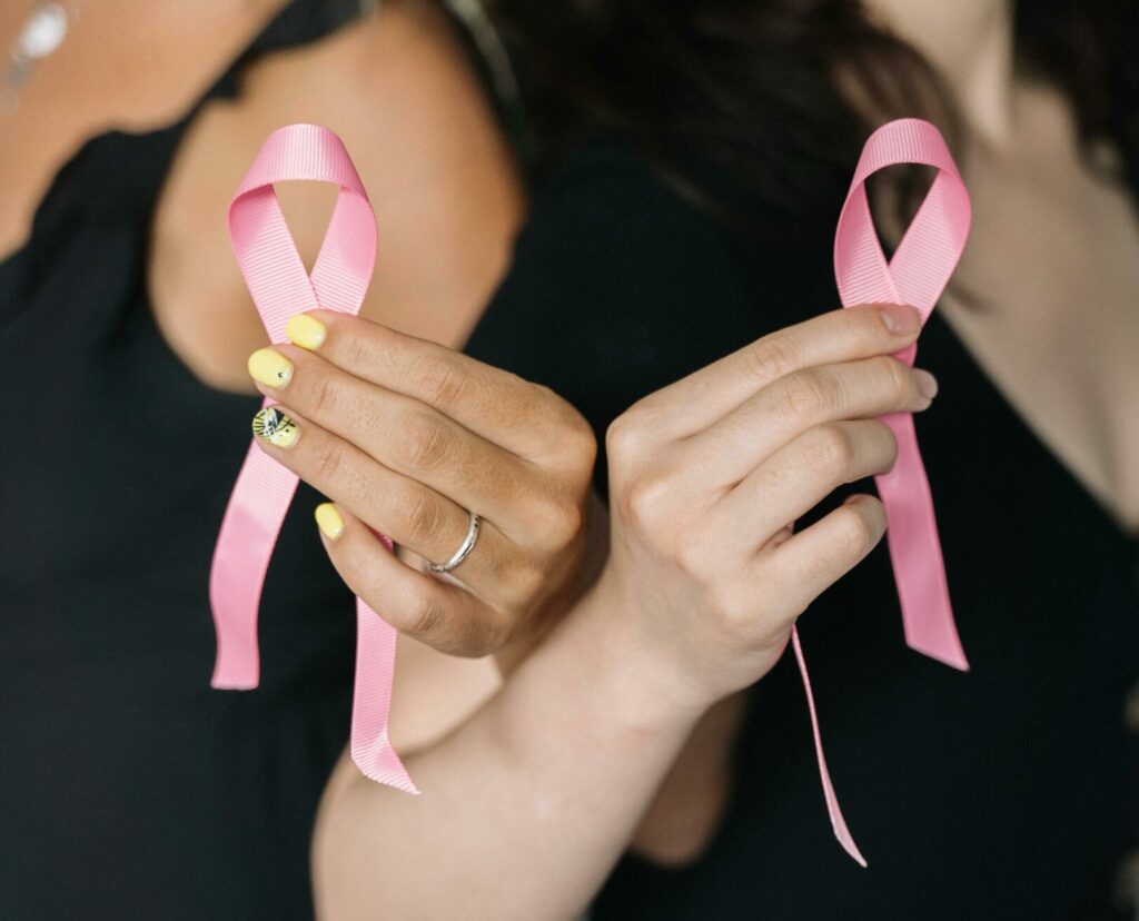 Two women hold up pink breast cancer ribbons to support a friend with breast cancer.