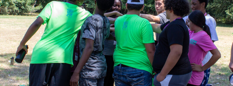 A group of teens tand together in a circle at Teen Retreat.