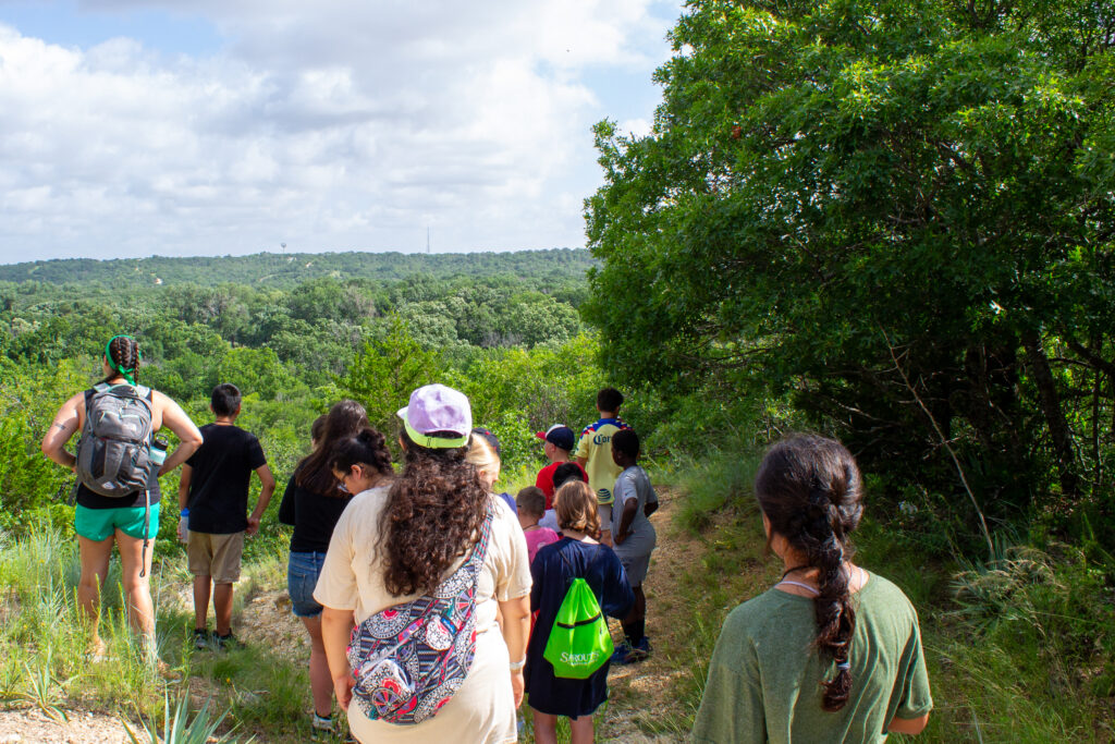A group of pre-teens stand in a group overlooking a scenic view at CampCARE 2024.