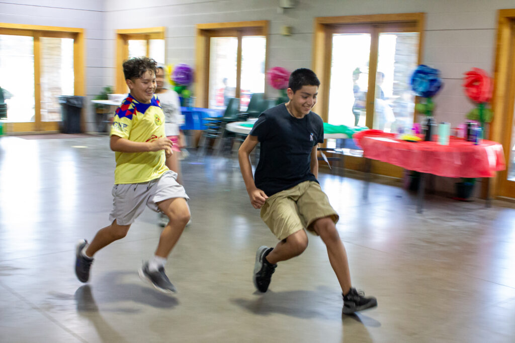 Two pre-teen boys race during a game at CampCARE 2024.