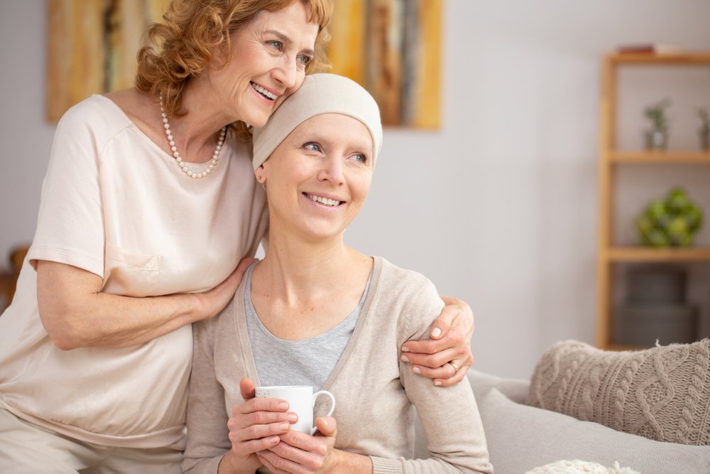 An older white woman hugs the shoulders of a younger white woman in a headwrap.