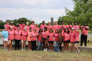 A diverse group of teenagers pose in front of a lake at Cancer Care's Teen Retreat 2024.