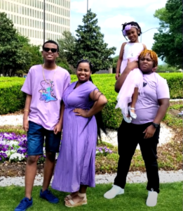 A family with a mother, two teenage soons, and a young sister pose together.